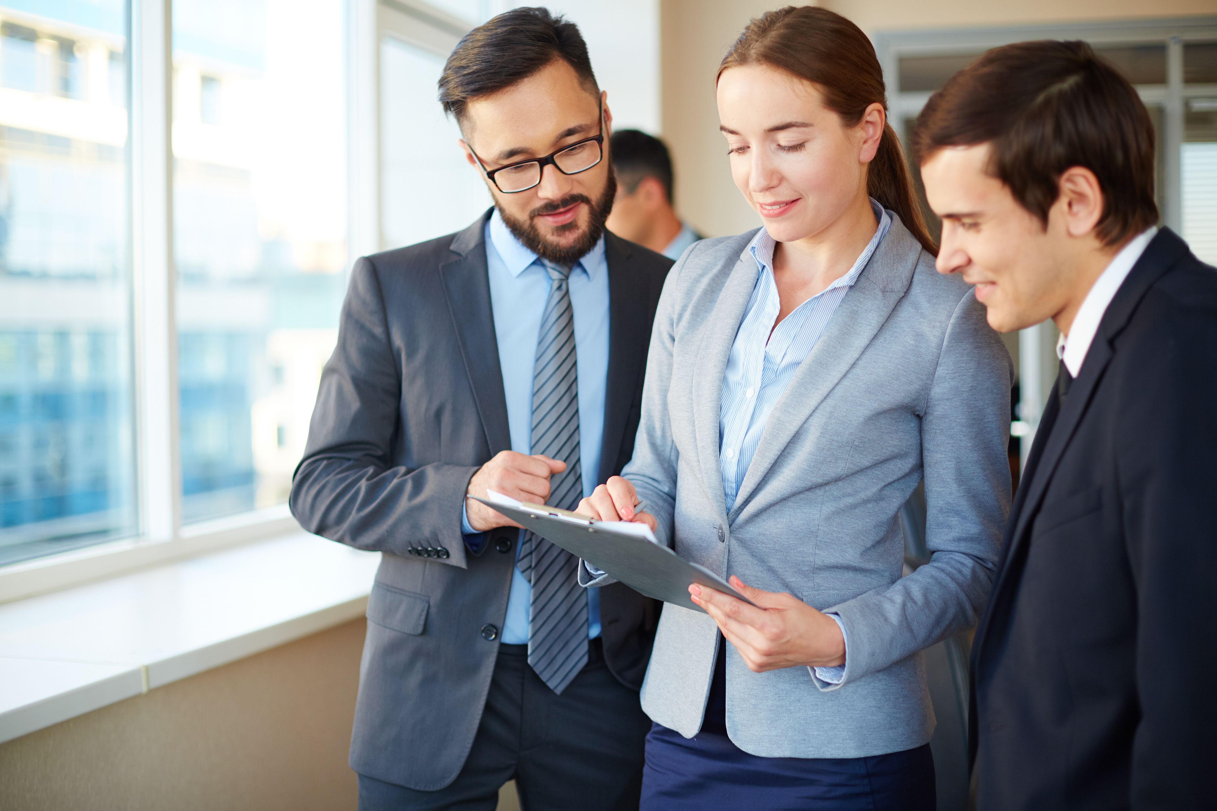 Confident businesswoman with clipboard consulting her partners in office